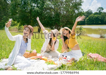 Asian woman friends, they are having picnic, eating in the morning, They are taking pictures to check in.