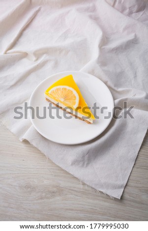 Slice of Lemon Cheesecake on white plate on wooden background