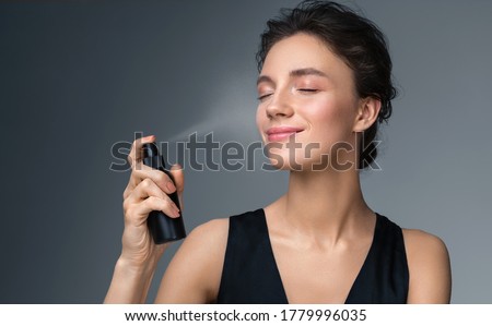 Woman using  finishing spray. Photo of woman with perfect makeup on gray background. Beauty concept Royalty-Free Stock Photo #1779996035