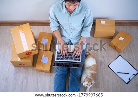 Asian men use computers to connect to the internet and connect with shoppers on websites or online sales channels. A man prepared the parcel to deliver the package to the customer. Small business