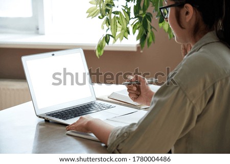 Indian young woman teacher student elearning remote training, watching webinar, video conference calling looking at laptop computer mock up screen working at home office using pc. Over shoulder view. Royalty-Free Stock Photo #1780004486