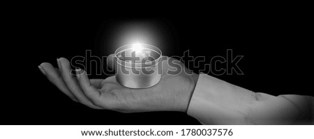 Candle in hand burning on the black background.