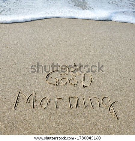 Good morning handwritten on a sandy beach with soft wave