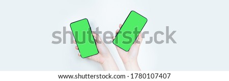 web banner contactless in new normal concept from two woman hand hold smart phone with green screen on white isolated background