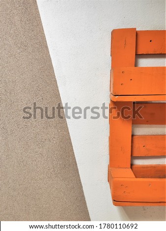 Background for text. Simple wall, beige and brown background. Wooden shelves, pallets, bright colors: blue, yellow, orange, red. Textural background with bright elements. Colored pallets with plant