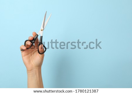 Female hand holds hairdresser scissors on blue background Royalty-Free Stock Photo #1780121387