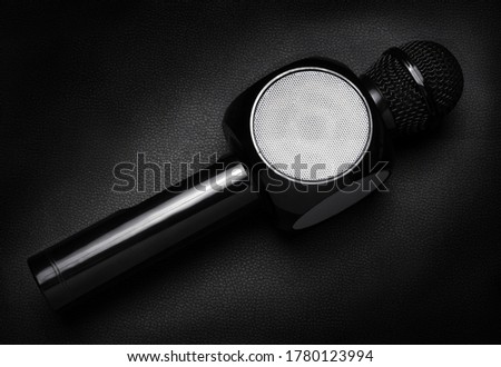 black wireless microphone with built-in speaker, for use in karaoke on a black background