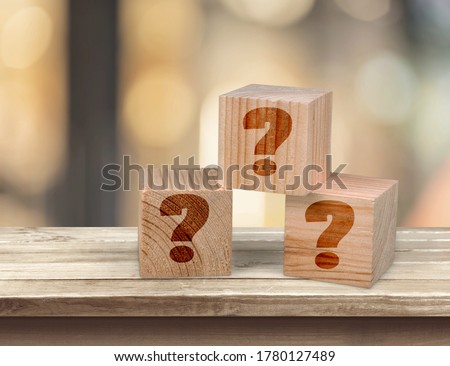 Wooden cube block  with sign question mark symbol on wood table.