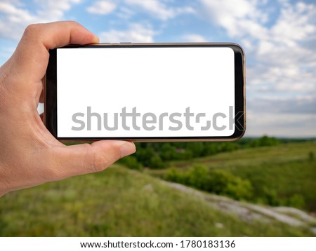 Hand holding smart phone with blurred backgroung. Blank screen for montage. Mockup image.