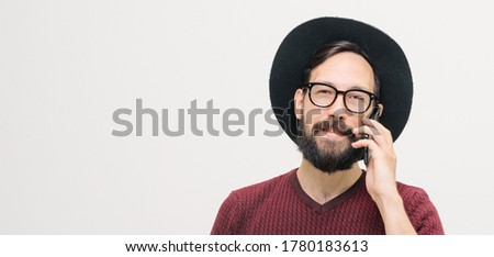  cheerful young man with a beard talking on a mobile phone. close-up portrait in studio. High quality photo