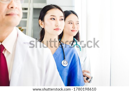 Group of doctor standing in line together and looking out of the windows at hospital.