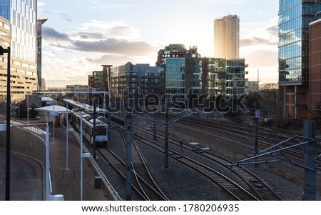 sunset in a city with shadows of tall buildings in summer with a train coming