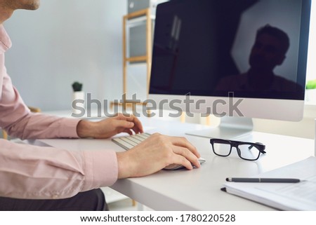 Crop anonymous male employee working on desktop computer in office