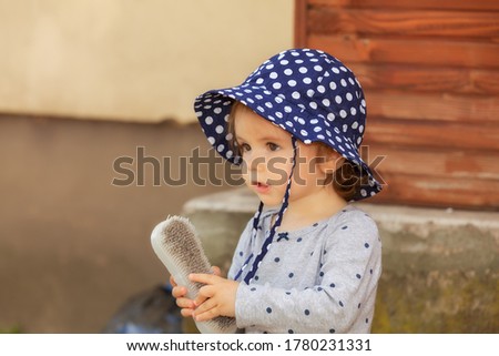 Beautiful toddler with blue hat playing in the backyard of the house, note shallow depth of field.