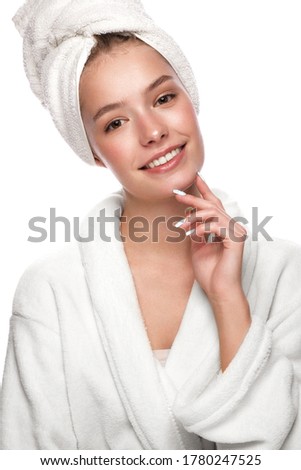 Beautiful tender young girl in a white towel with clean fresh skin posing in front of the camera. Beauty face. Skin care. Photo taken in studio on a white isolate background.