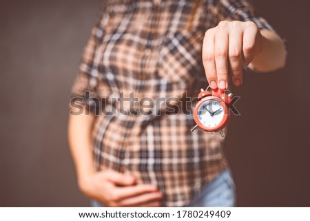pregnancy time concept, motherhood, people and expectation idea. Toned photo of pregnancy. Pregnant woman holds a clock.