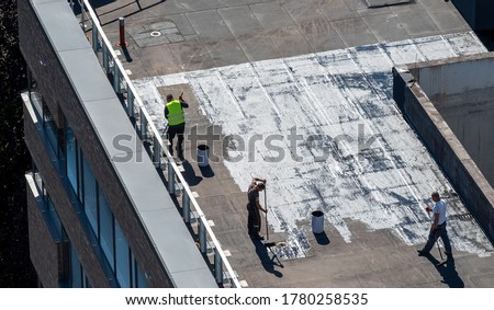 Birds eye view of a roof construction site. Professional bitumen waterproofing on a flat building. Royalty-Free Stock Photo #1780258535