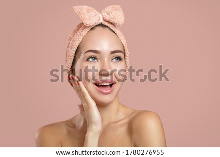 The bright young woman shows surprise. Open mouth and smile. Hand on her face. Clean skin