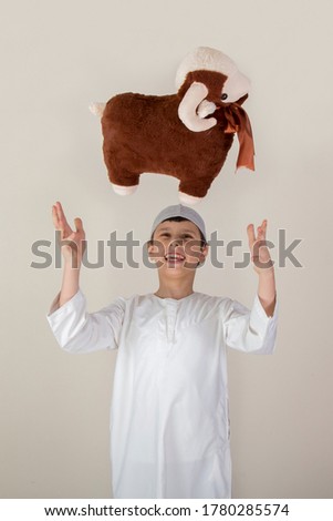 Little Muslim kid playing with sheep toy - celebrating Eid Al Adha - Happy Sacrifice Feast Royalty-Free Stock Photo #1780285574