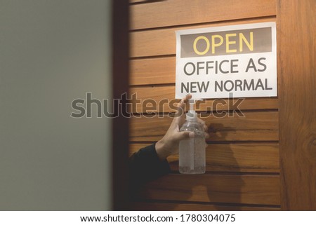 Business owner hand is holding alcohol gel to label for open office. The concept is opening office after the COVID-19 situation, follows the new normal life. select tive focus