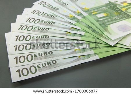 Stack of various one hundred euro bills, one hundred euro cash bills on dark background.