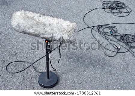 Windproof. Microphone in wind protection. Large street microphone in windproof fur. Professional equipment for video operators. Microphone stands asphalt. Concept - selling professional microphones