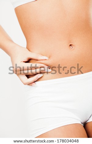 Young woman pinching waist and checking her body fat.