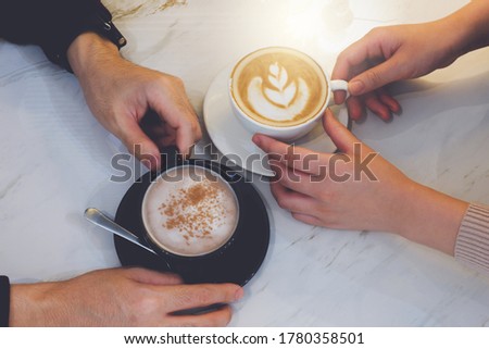 Close up image of two people having a hot coffee in a cafe.