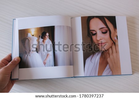 Open photobook with bride on white wooden table