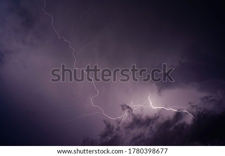 A bright flash of lightning against the dark purple night storm sky