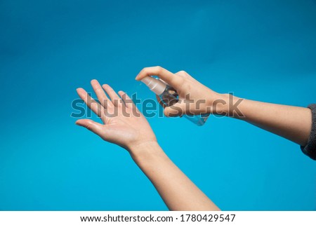 Spraying a hand sanitizer from a transparent mist spray bottle to the hand