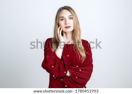 Picture of stylish Attractive European young woman with long blonde hair keeps hand on neck. European young woman isolated over white background.