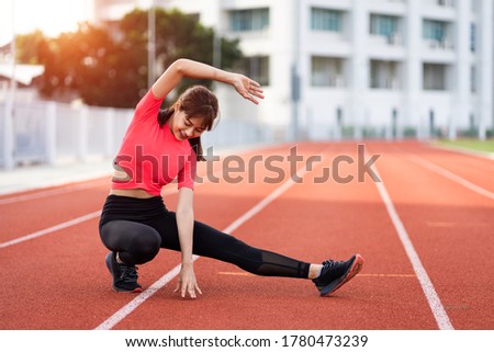 Portrait of a young woman runner warm up and stretching before workout in the morning in city stadium. Healthy and recreation stock photo.