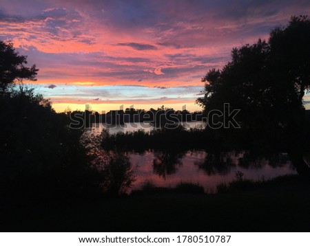 A picture of an intense pink and purple sunset reflected over a river. 