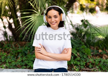 Young caucasian woman with headphones at outdoors keeping the arms crossed in frontal position