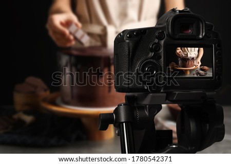 Food photography. Shooting of chef decorating chocolate cake, focus on camera