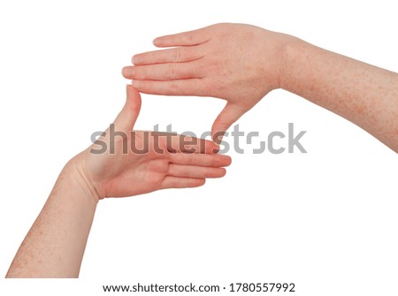 Freckled white hands, making a square or rectangle frame between thumb and index finger with fingers together. Female hand isolated