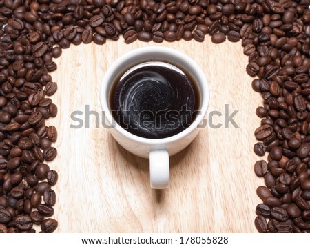 A cup of coffe on breadboard with coffee grains