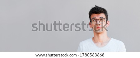 Handsome man rolls eyes on grey background