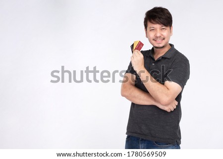 Happy Asian man in the smiley face holding three credit card, look at the camera, studio light portrait isolated on white background, credit card concept
