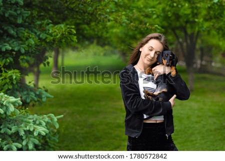 dachshund. In the summer in the garden, a girl with her favorite dachshund puppy