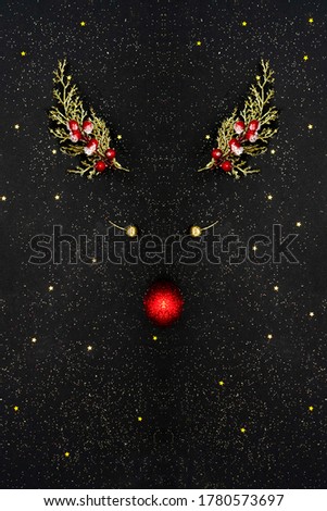 Christmas deer concept made of golden branches, red and gold balls decoration on black starry background. Flat lay top view composition. Minimalism.