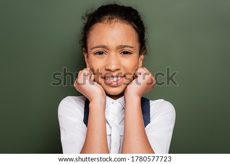scared african american schoolgirl near empty green chalkboard