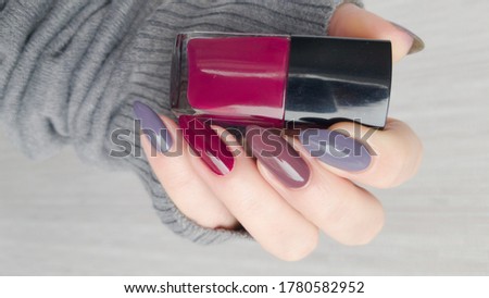 Female hand with long nails and multi-colored manicure, bottles of nail polishes