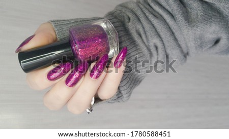 Woman's hands with long nails and pink fuchsia bottle manicure with nail polish