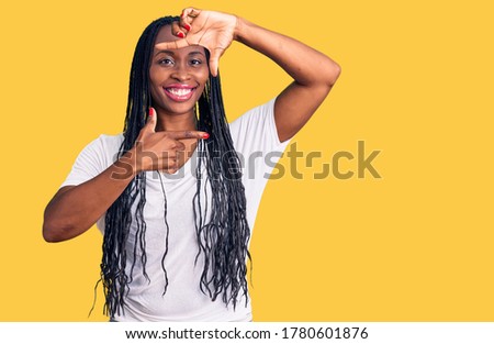 Young african american woman wearing casual clothes smiling making frame with hands and fingers with happy face. creativity and photography concept. 
