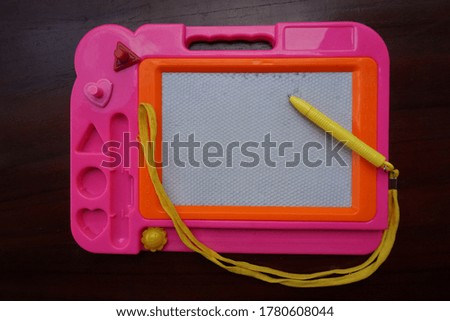white board with pink frame with yellow pen on wooden board - noise texture background, out of focus and grainy blurred background