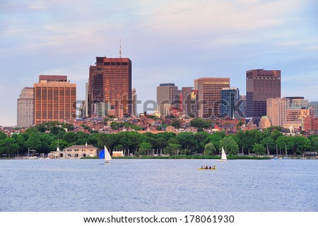 Boston sunset over Charles River with urban skyscrapers and boat.