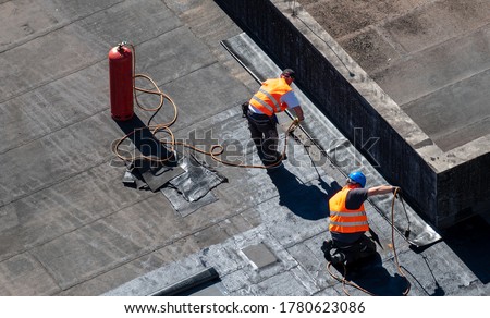 Birds eye view of a roof construction site. Professional bitumen waterproofing on a flat building. Royalty-Free Stock Photo #1780623086