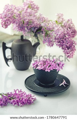 Cup of tea with lilac flowers on a light background. Mocap for postcards. Spring. Vase with lilac. Copy space. concept of holidays and good morning wishes